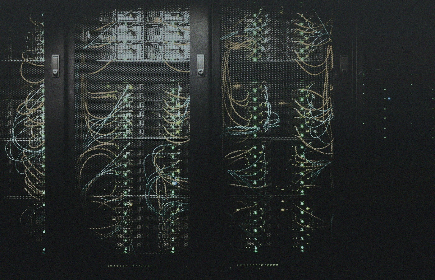 Dim server racks behind mesh doors with status lights and cables, no people or brand logos — always-on compute mood for a desk AI box
