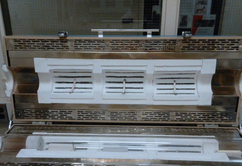Empty CVD furnace and quartz tube with a wafer boat on a lab bench, no people.