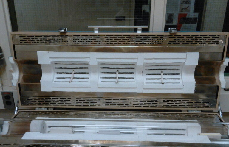 Empty CVD furnace and quartz tube with a wafer boat on a lab bench, no people.