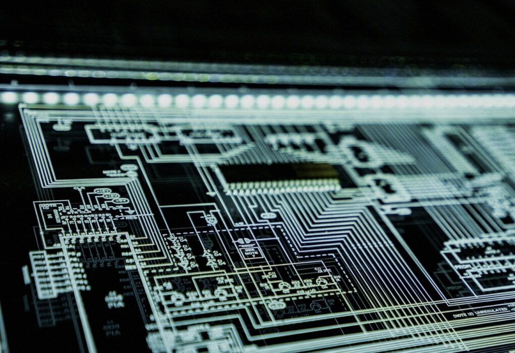 Angled close-up of a glowing teal circuit schematic panel on a dark surface, face-free cybersecurity still for Anthropic distillation and Moonshot IPO coverage