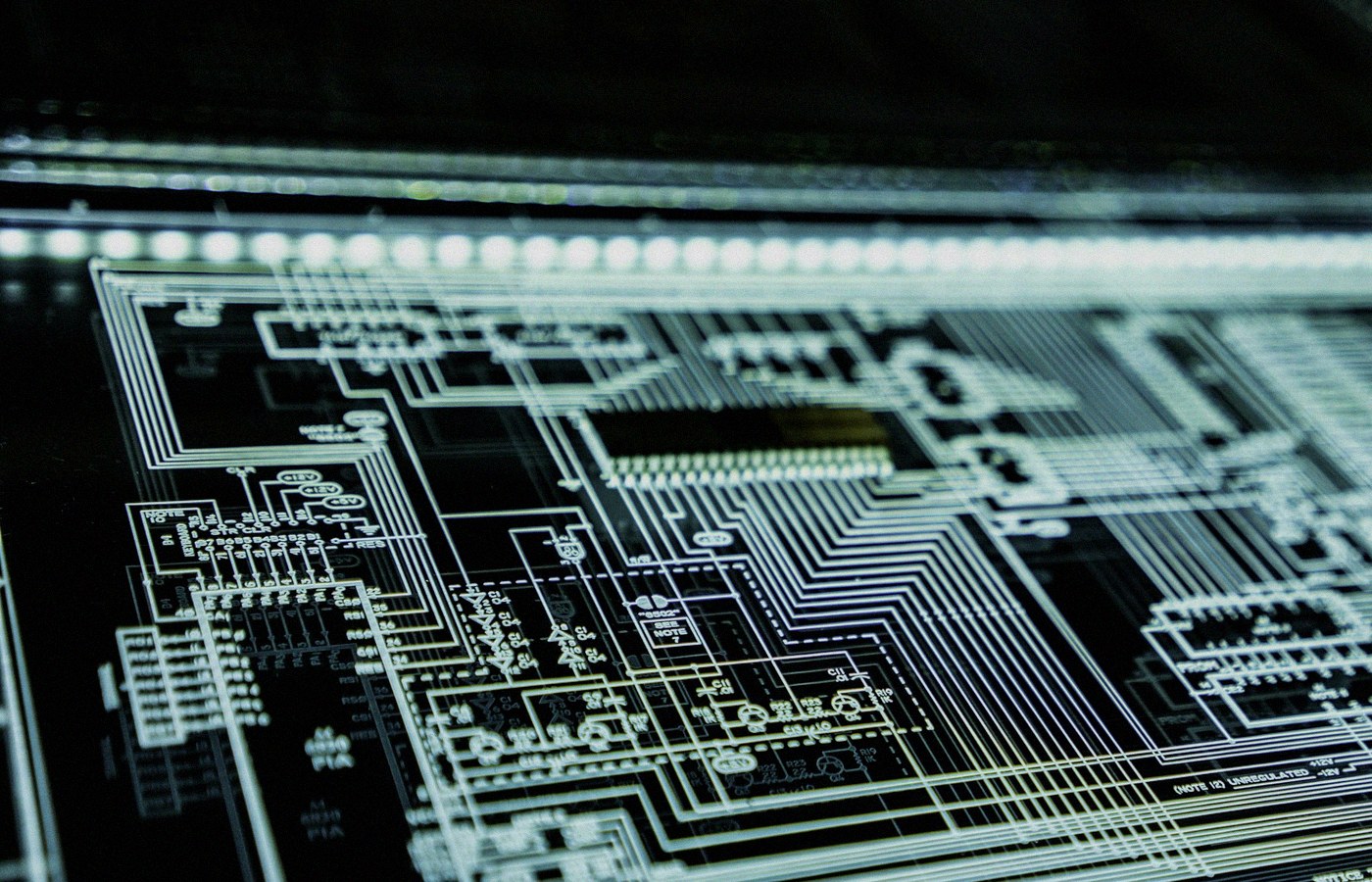 Angled close-up of a glowing teal circuit schematic panel on a dark surface, face-free cybersecurity still for Anthropic distillation and Moonshot IPO coverage