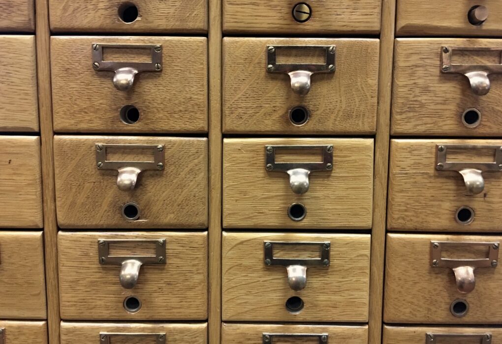 Close-up of wooden library card catalog drawers with blank brass label holders