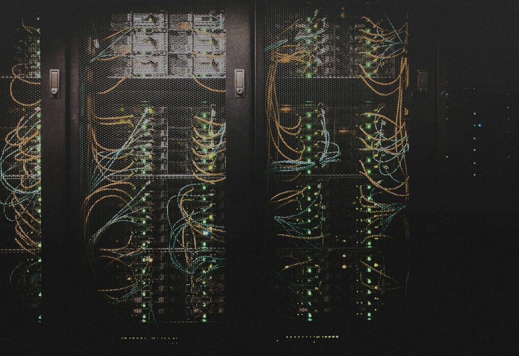 Face-free data-center server racks with dense network cabling and status LEDs in a dim aisle — related compute and infrastructure still for Mistral AI Series D sovereign AI funding coverage