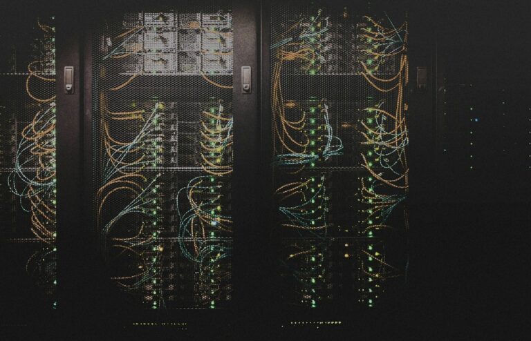 Face-free data-center server racks with dense network cabling and status LEDs in a dim aisle — related compute and infrastructure still for Mistral AI Series D sovereign AI funding coverage