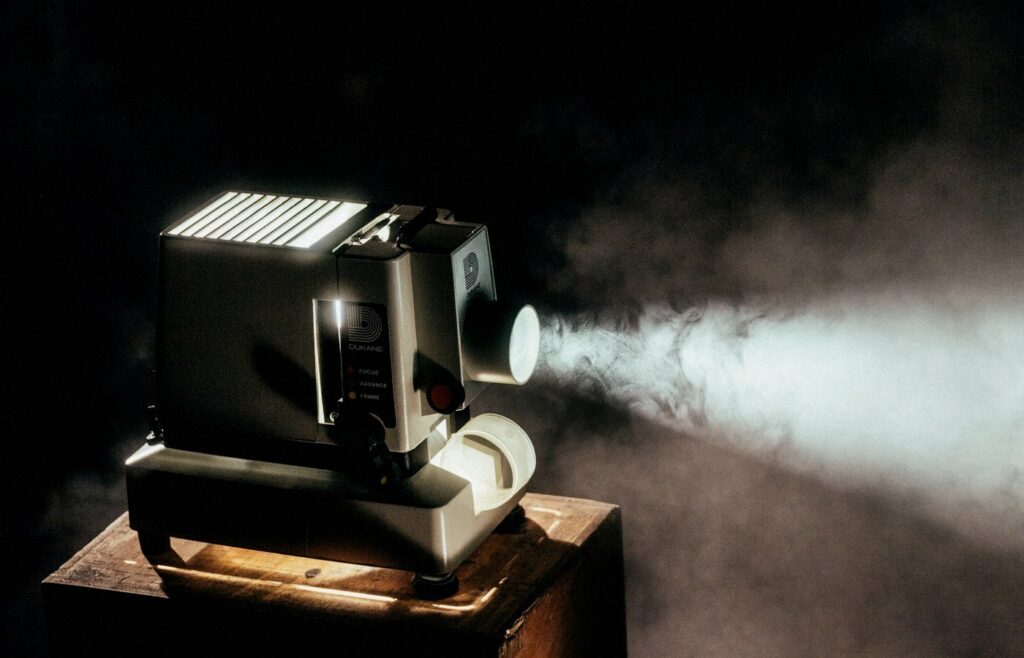 Vintage Dukane filmstrip projector casting a bright beam in darkness, face-free still for Google DeepMind Gemini agentic video understanding