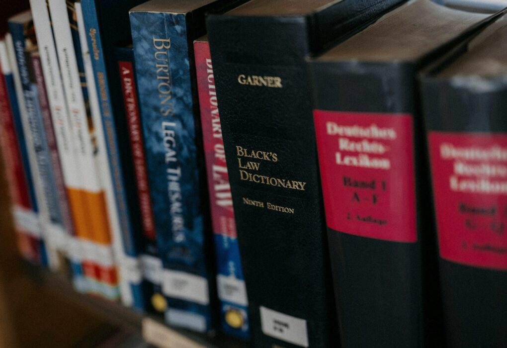 Face-free row of law books lined up on a wooden shelf — legal research metaphor hero still for Harvey legal AI $550M round at $15.5B valuation and Guardrails AI acquisition Sep 9 2026