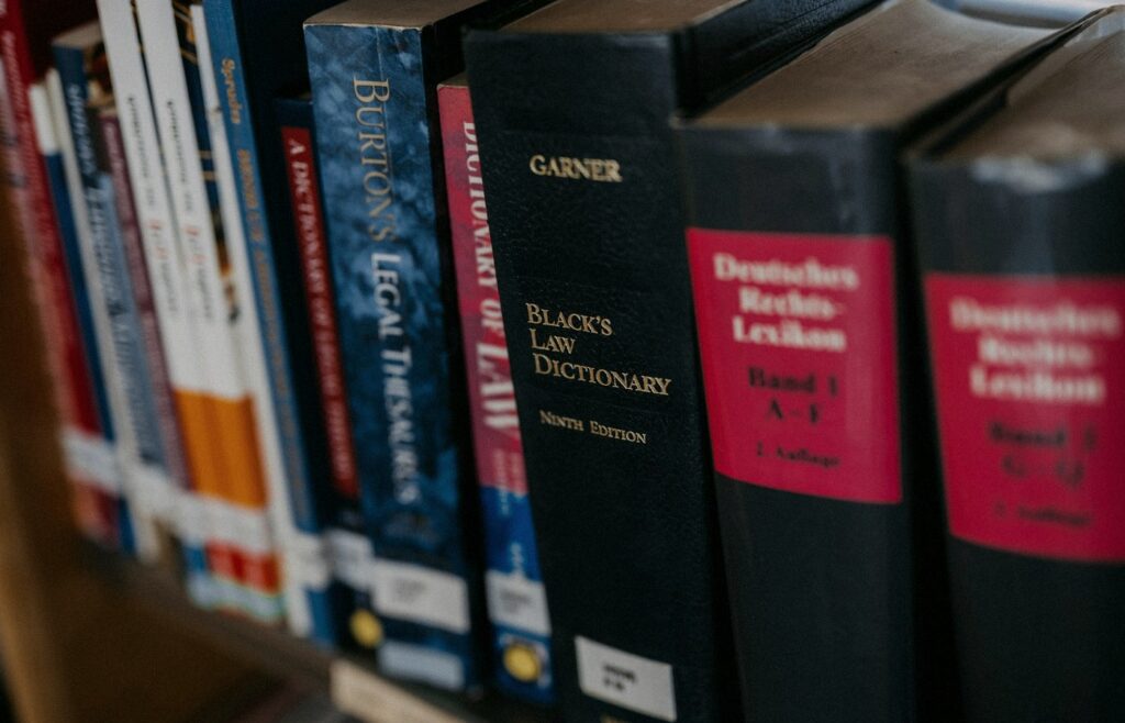 Face-free row of law books lined up on a wooden shelf — legal research metaphor hero still for Harvey legal AI $550M round at $15.5B valuation and Guardrails AI acquisition Sep 9 2026
