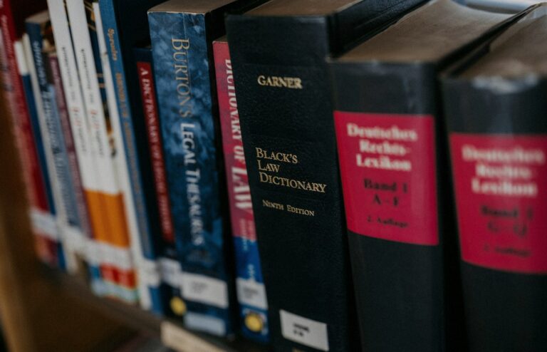 Face-free row of law books lined up on a wooden shelf — legal research metaphor hero still for Harvey legal AI $550M round at $15.5B valuation and Guardrails AI acquisition Sep 9 2026