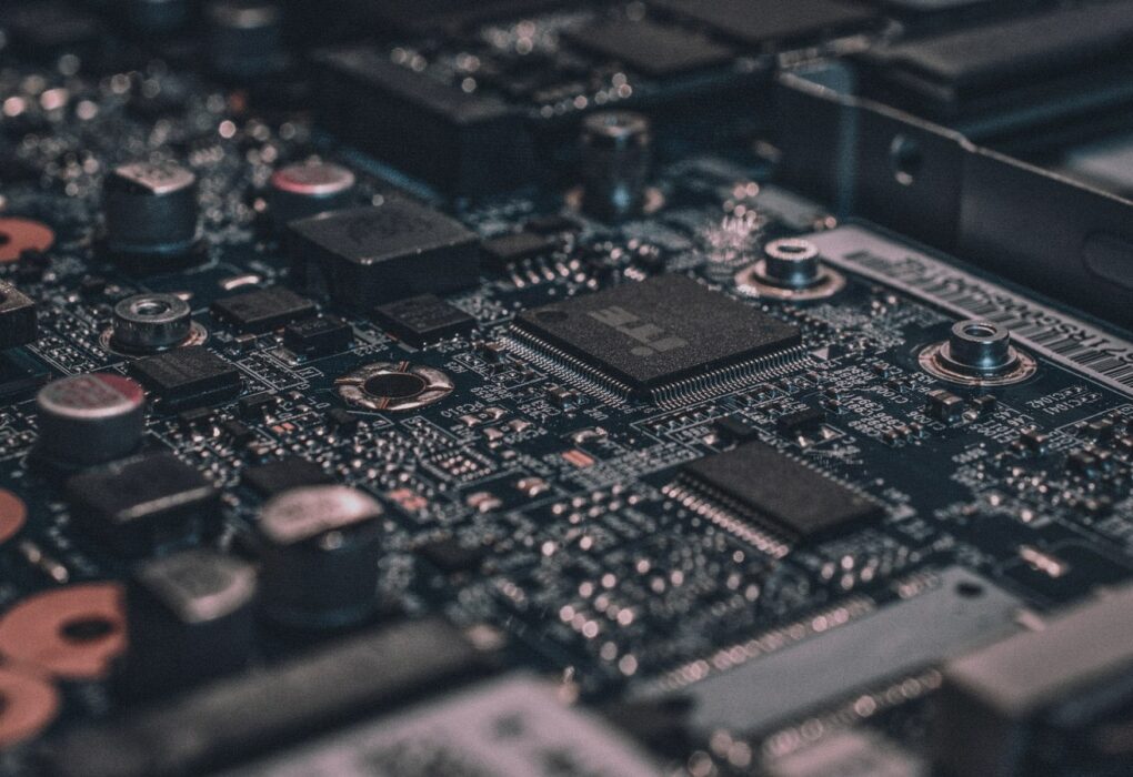 Macro close-up of a dark circuit board with a central sensing chip and dense surface-mount parts, face-free silicon still for Lyte Series C robot perception coverage