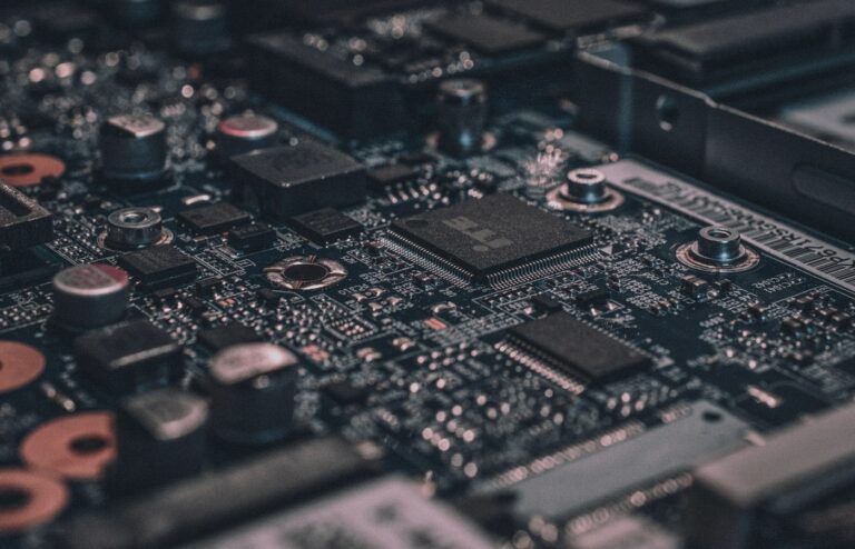 Macro close-up of a dark circuit board with a central sensing chip and dense surface-mount parts, face-free silicon still for Lyte Series C robot perception coverage