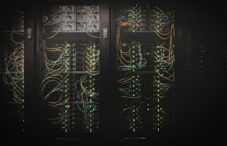 Face-free server racks with illuminated blue green and orange network cables behind mesh panels — related home-LAN multi-node compute still for NVIDIA PAIR Personal AI Router local inference coverage