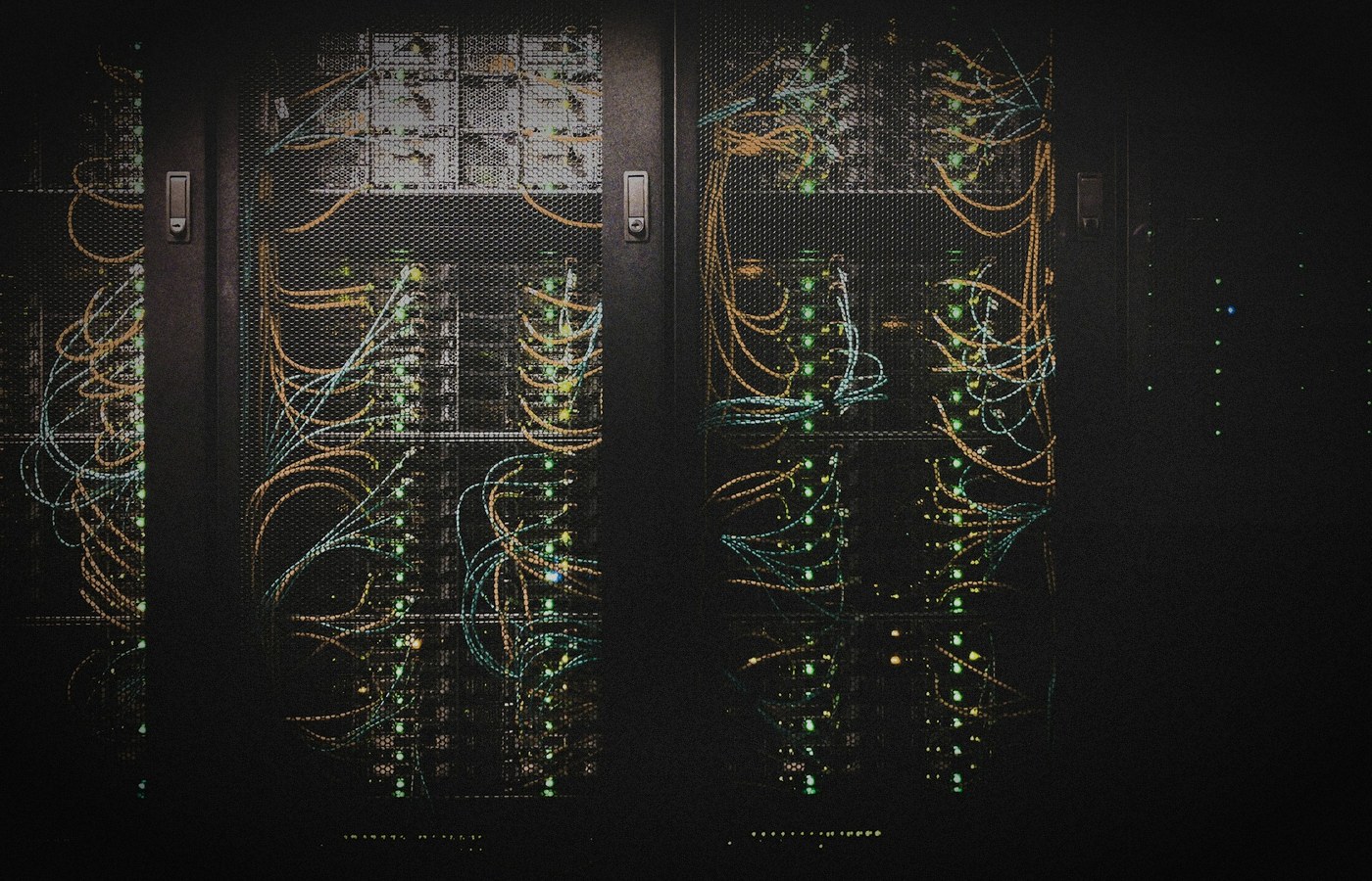 Face-free server racks with illuminated blue green and orange network cables behind mesh panels — related home-LAN multi-node compute still for NVIDIA PAIR Personal AI Router local inference coverage