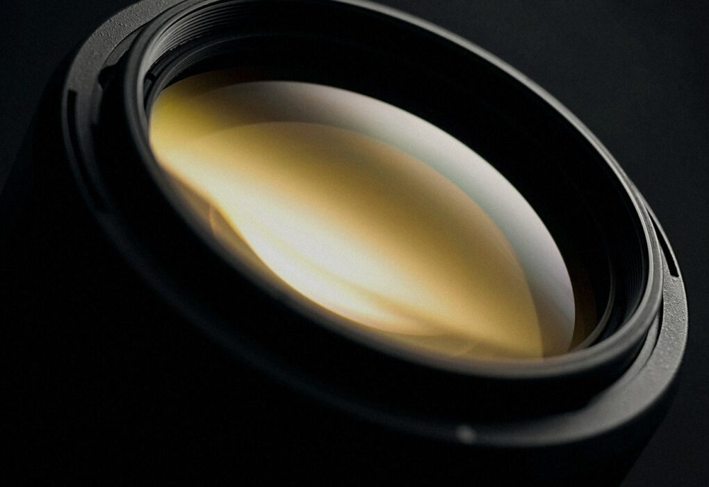 Face-free Unsplash macro of a camera lens glass element on a dark background — related still for reported OpenAI Glass Imaging camera-AI acquisition September 2026