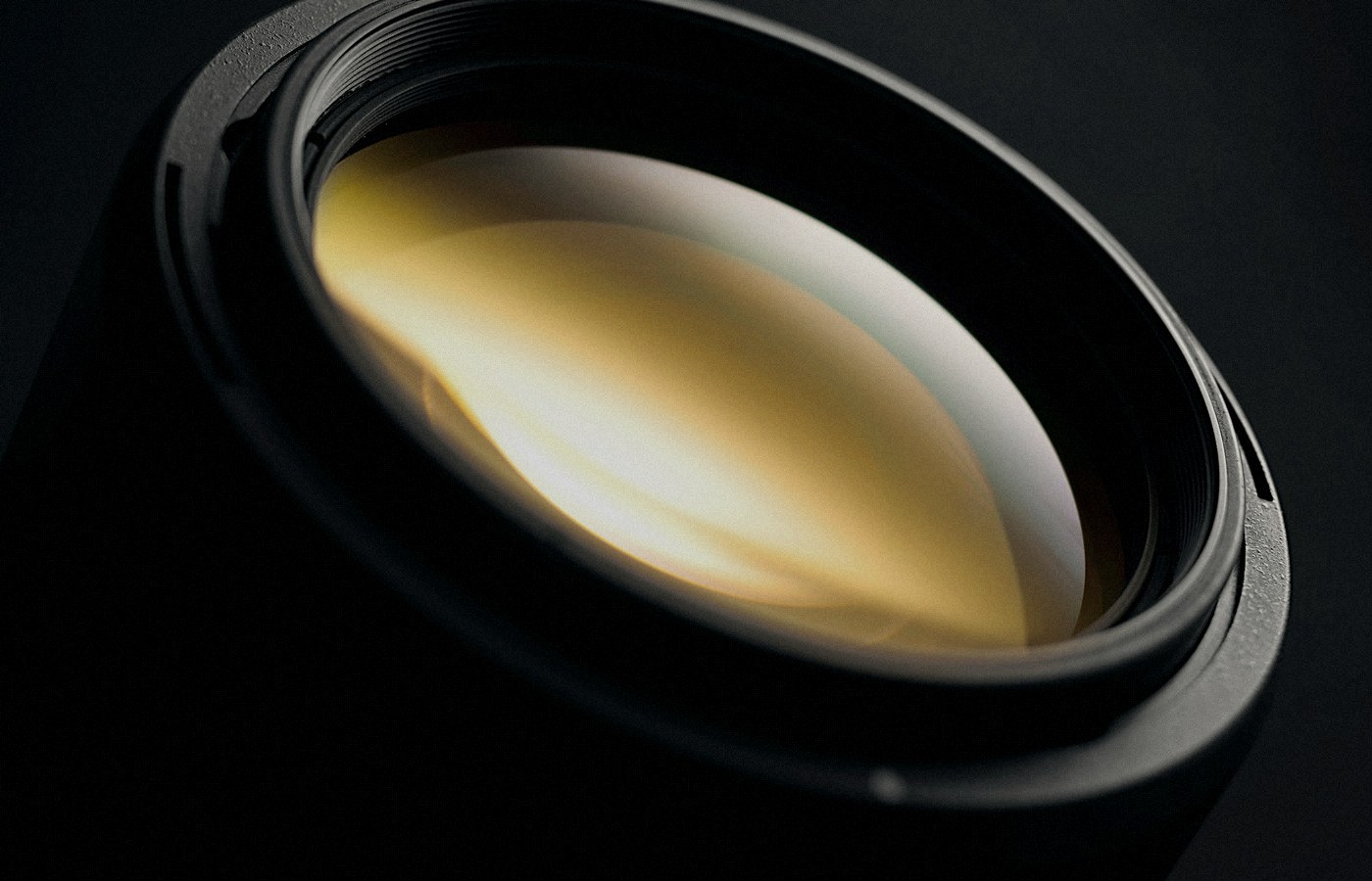 Face-free Unsplash macro of a camera lens glass element on a dark background — related still for reported OpenAI Glass Imaging camera-AI acquisition September 2026