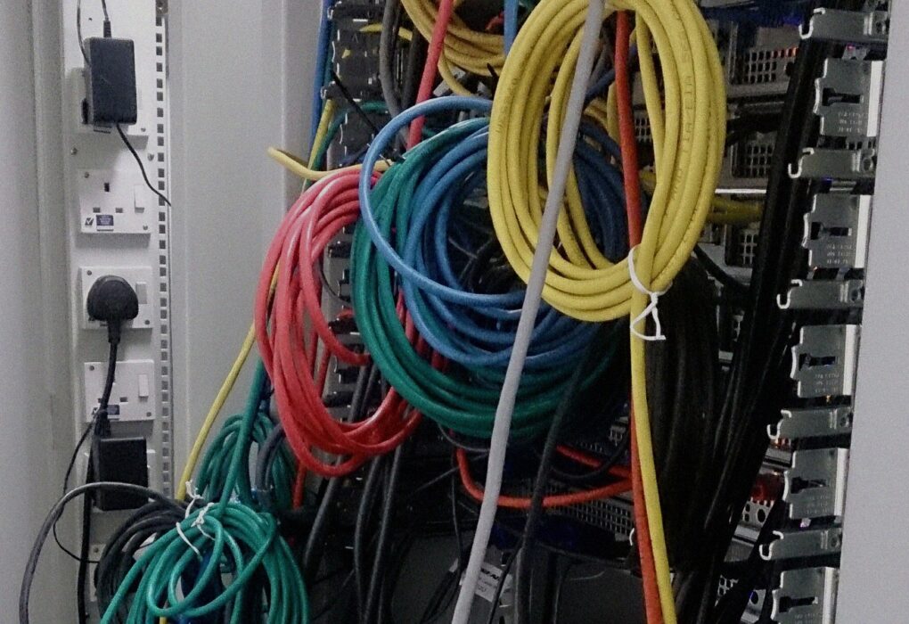 Face-free close-up of dense network cables and patch connections in a server room — still for OpenAI German wiki incident and misalignment reporting framework coverage