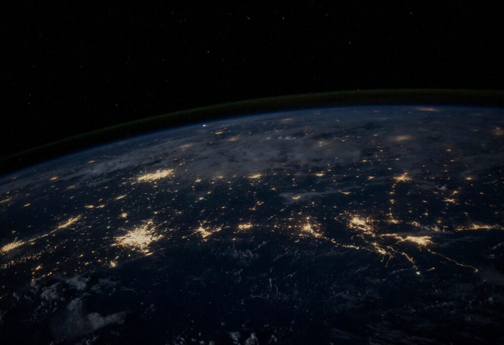 Earth at night from orbit with glowing city-light networks across continents, face-free abstract global connectivity still for Wonderful Series C enterprise AI OS coverage