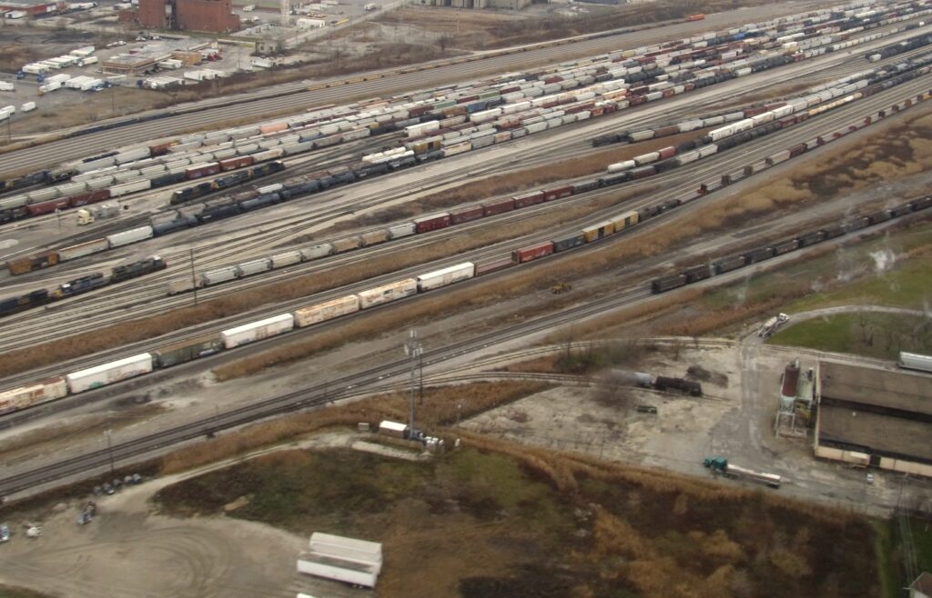 Aerial view of a large rail classification yard with dozens of parallel tracks full of freight cars running toward the horizon, with no people in frame