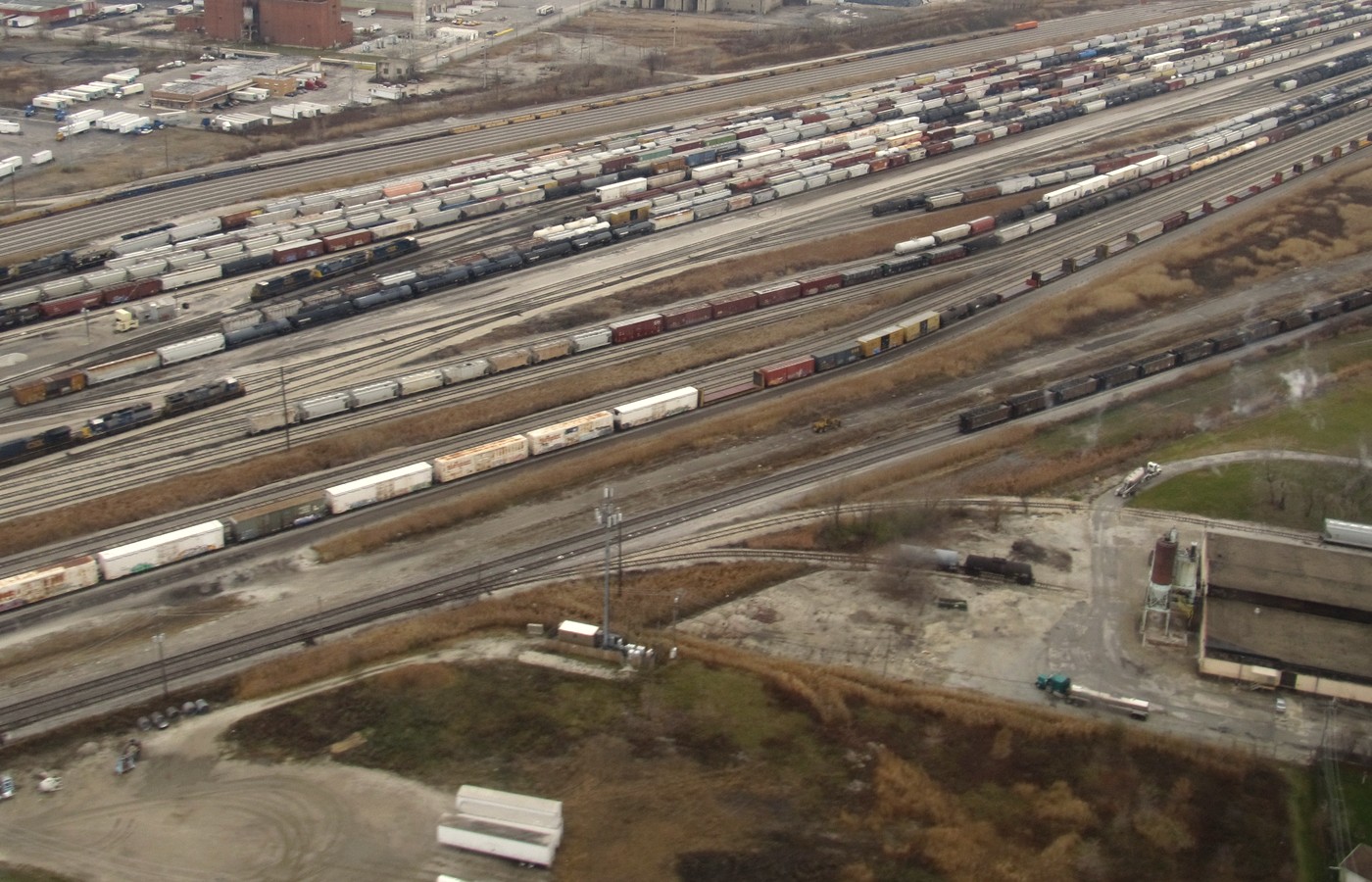Aerial view of a large rail classification yard with dozens of parallel tracks full of freight cars running toward the horizon, with no people in frame