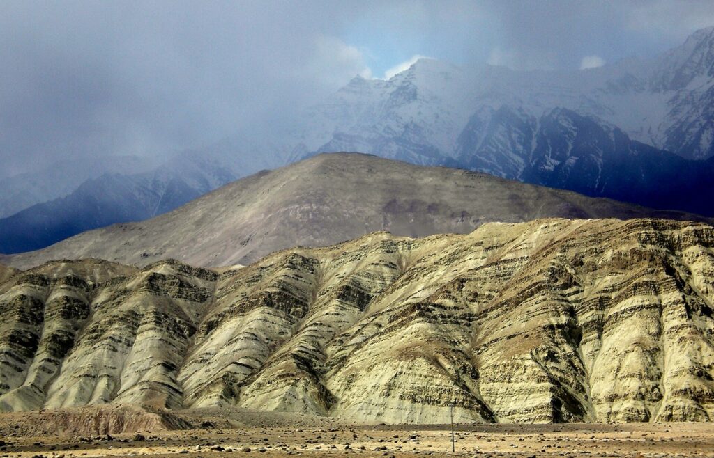 Tilted sedimentary rock layers in an arid mountain landscape under cloud, with no people in frame