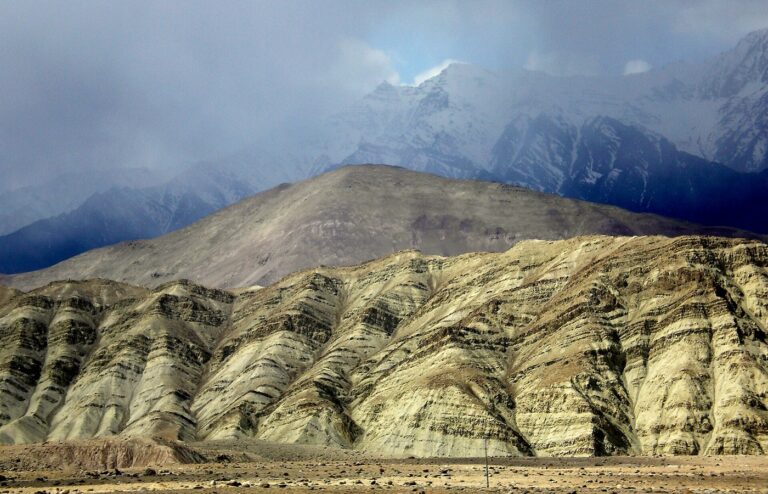 Tilted sedimentary rock layers in an arid mountain landscape under cloud, with no people in frame
