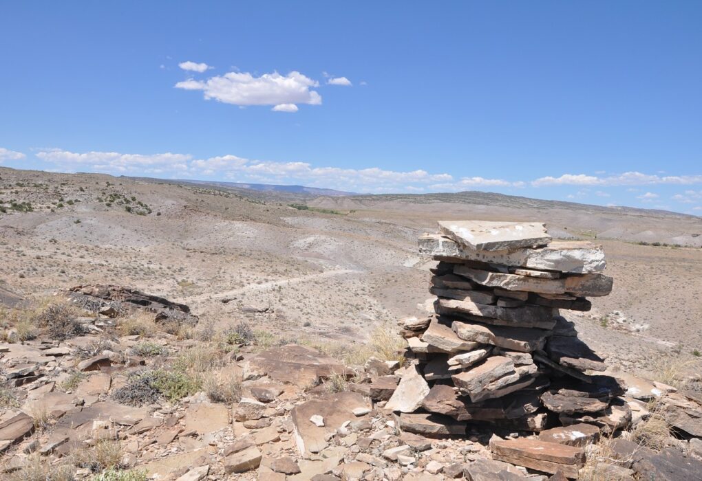 A stacked-stone trail cairn on a dry Utah desert ridge under a blue sky